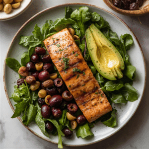 Plate with salmon, avocado, olives, and leafy greens — keto mediterranean diet hybrid meal.